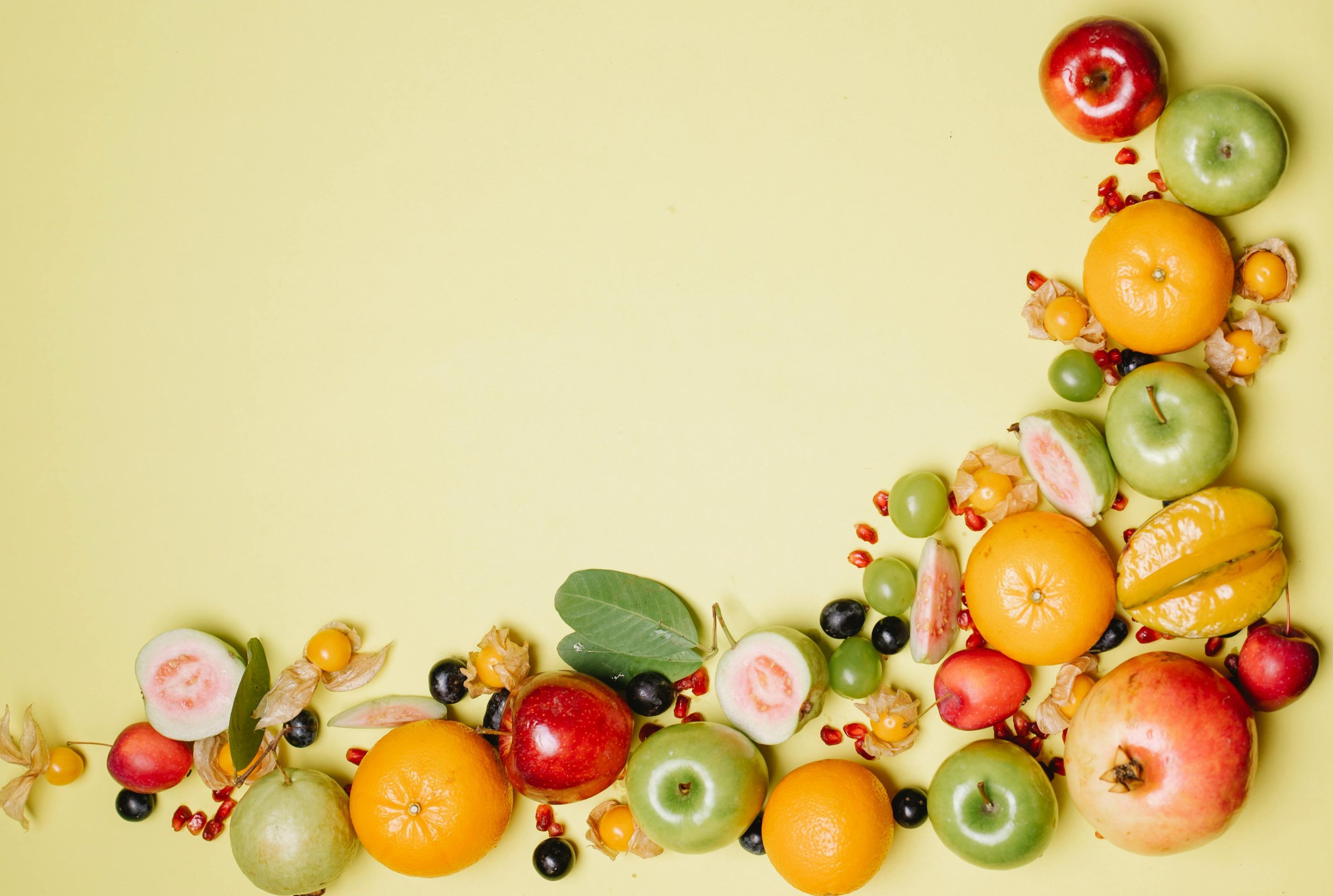 Draufsicht auf verschiedene köstliche, reife, saftige Früchte und Beeren vor beigem Hintergrund